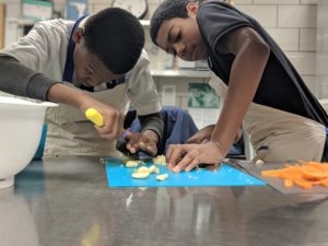 Two middle-school-aged male students chop garlic at the Detroit Food Academy.